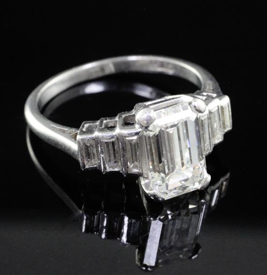 A 1930s/1940s Art Deco platinum and single stone emerald cut diamond ring, with graduated baguette cut diamond set shoulders,